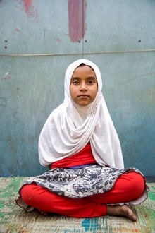Portrait eines Mädchens mit Kopftuch, das auf einer bunten Straße in Kalkutta steht.