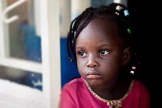 Mädchen aus Uganda mit lächelndem Gesicht in lebendigem Umfeld