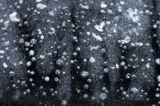Photo art by Ezra Portent: Frozen air bubbles on an ice surface, capturing winter's essence.