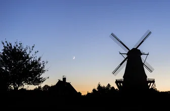 Photo art: silhouette of a historic mill against a blue evening sky