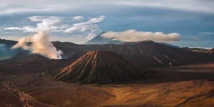 Panoramic view of Mount Bromo in Indonesia, featuring gentle hills and a cloudy sky.