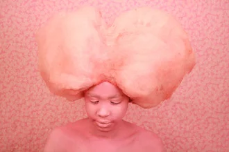 Fotokunst von Enora Lalet: Kind mit Zuckerwatte, fröhliches Gesicht und bunte Farben.