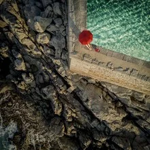 Photo art by Ambra A: legs waiting by the pool under a red umbrella.