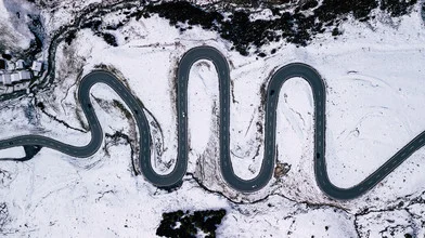 Aerial view of a winding road through snow-covered mountains in Switzerland