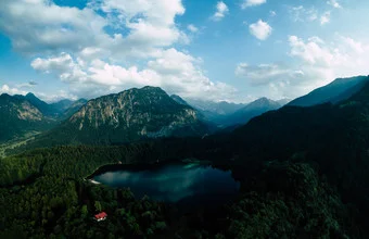 Photo art by Rémi Peschet: red house surrounded by green forests in the Alps