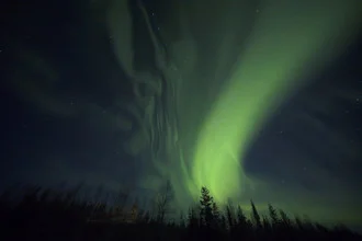 Photo art by Dirk Heckmann: northern lights dance over the Finnish night sky.