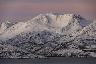 Pastellfarbene Winterstimmung in Norwegen mit schneebedeckten Bergen und ruhigem Wasser.
