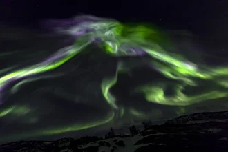 Intense polar lights over a Norwegian winter landscape