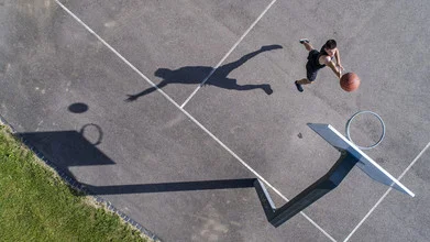 Schatten eines Basketballspielers im Wurf, draußen auf dem Spielfeld.