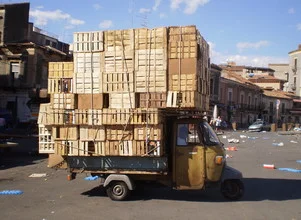 Photo art by Mario Stuchlik: vibrant market scene with quirky vehicle and boxes.
