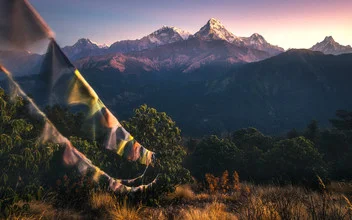 Fotokunst mit bunten Gebetsfahnen vor dem Himalaya im sanften Licht des Sonnenaufgangs.
