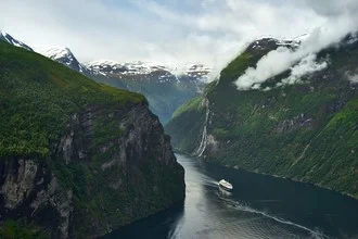 Photo art by Alex Wesche: moody ferry in a Norwegian fjord under cloudy skies.