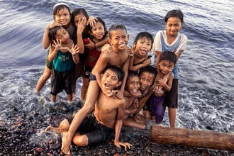 Children joyfully playing on a Balinese beach, with the ocean in the background.