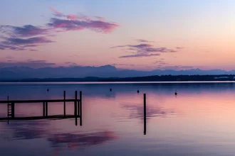 Friedliche Szenerie am See im Zwielicht, sanfte Farben und Spiegelungen auf dem Wasser.
