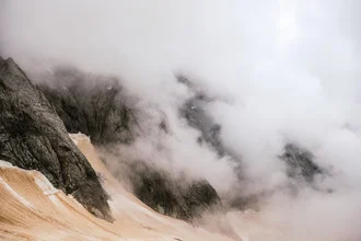 Clouds over rocky mountains in France, moody atmosphere with soft gray tones.