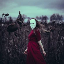 Woman wearing a surreal red mask, surrounded by autumn colors.