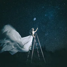 Woman under a starry sky reaching for the stars, dreamlike atmosphere.