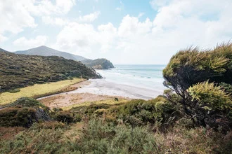 Beautiful beach in New Zealand with gentle waves and clouds in the sky