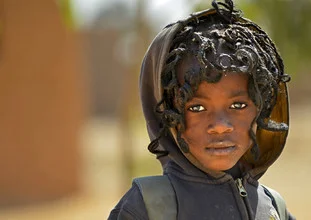 Photo art of a school kid in Burkina Faso, smiling warmly.