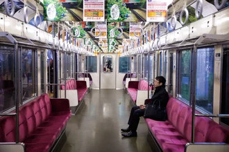 Fotokunst von Oona Kallanmaa: eine entspannte Zugfahrt durch Japan mit Menschen und lila Wänden.