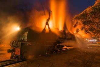Night photo of a steam train with the Victoria Falls in Zimbabwe in the background.