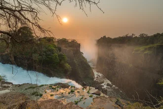 Fotokunst von Dirk Steuerwald: ruhiger Wasserfall im orangefarbenen Licht des Sonnenaufgangs