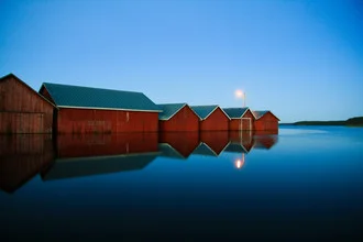Fotokunst: nächtliche Bootshäuser spiegeln sich friedlich im See