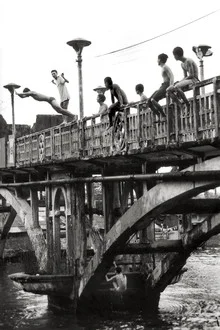 Young men jumping from an old Chinese bridge into the Saigon River