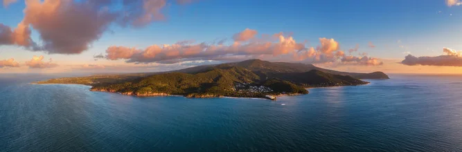 Aerial view of a Caribbean island at sunset with soft clouds and calm sea.