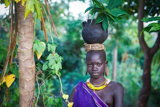 Portrait of a Suri woman in a garden, surrounded by lush greenery in Ethiopia.