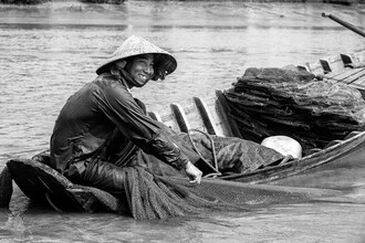 Fisherman in the Mekong Delta sitting calmly in a boat, surrounded by water and green nature.