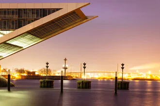 Sonnenuntergang über dem Hamburger Hafen mit ruhigem Wasser und sanften Farben.