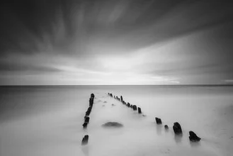 Black and white photo of the Baltic Sea beach with gentle waves and clouds.