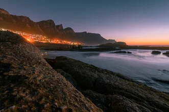 Nächtliche Sicht auf Camps Bay mit sanften Wellen und Stadtlichtern.