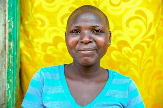 Woman smiling in front of a yellow door in Nairobi, vibrant colors in the background.