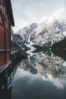 Calm winter landscape featuring a snowy lake with a cabin in the background