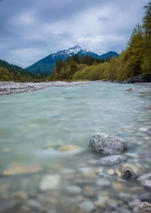 Mountain river in gentle colors, surrounded by trees and mountains, invites tranquility.