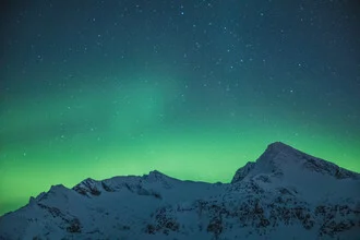 Photo art by Sebastian Worm: glowing mountain under the Northern Lights in Norway.