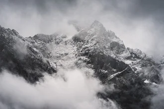 Mystic mountain beneath dark clouds, surrounded by fog and a serene atmosphere.