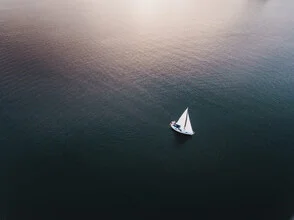 Photo art by Lina Jakobi: sailor at sunset on calm waters.
