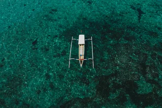 Drone shot of a fishing boat on calm water in Indonesia.