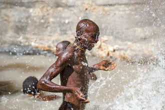 Fotokunst von Miro May: fröhlicher Wassertropfen-Splash am Flussufer in Äthiopien.