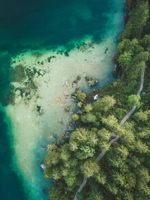 Aerial view of a mountain lake, surrounded by majestic Alps and lush forests.