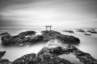 Traditionelles Torii an der Küste Japans, umgeben von Wasser und Felsen.