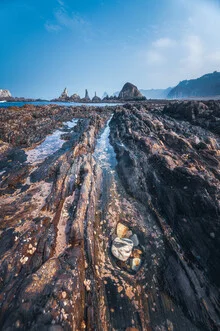 Photo art by Jean Claude Castor: rugged coastal image with rocks and gentle waves