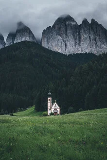 Fotografie einer Kirche vor schroffen Bergen und dramatischen Wolken in Südtirol.