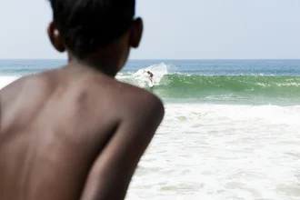Curious child on the beach in India, with waves and horizon in the background.