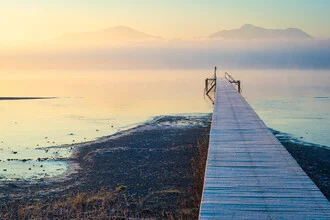 Wintermorgen am Chiemsee mit Nebel über den Bergen und sanften Farben am Himmel.