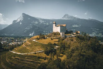 Photo art: small castle in Vaduz, surrounded by gentle hills and a calm sky.