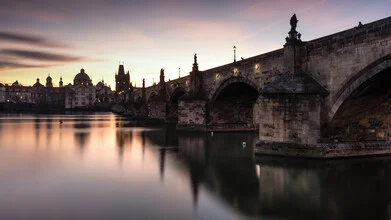 Sunrise over the Charles Bridge, soft colors reflecting in the water